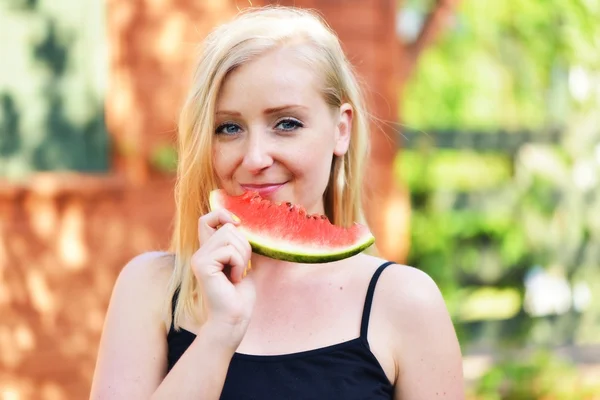 Junge Frau isst draußen Wassermelone. Lächelnd und glücklich. — Stockfoto