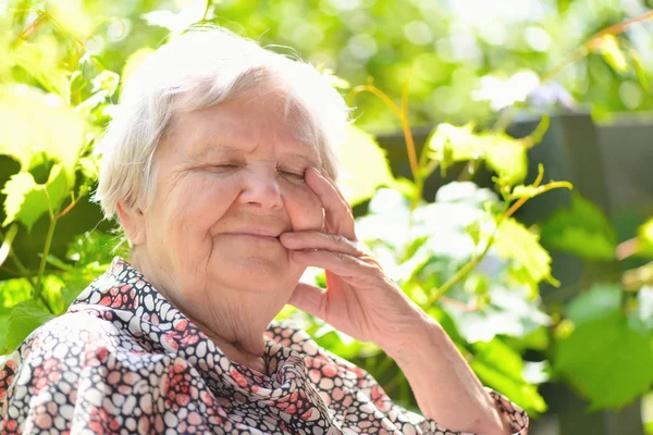Seniorin lächelt und träumt im Garten. — Stockfoto