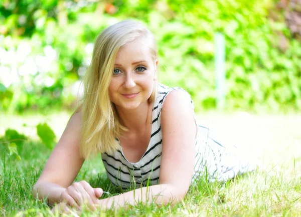 Young blonde woman woman laying on grass in park. — Stock Photo, Image