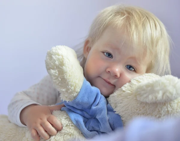 Cute baby with blue eyes hugging a mascot. — Stock Photo, Image