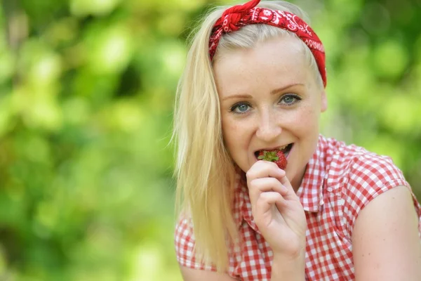 Junge attraktive Frau isst eine Erdbeere, im Freien. — Stockfoto