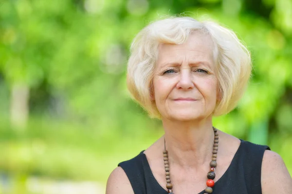 Mature, blonde woman in garden, — Stock Photo, Image