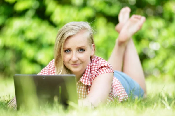 Young attractive woman lying on lawn with laptop. — Stock Photo, Image