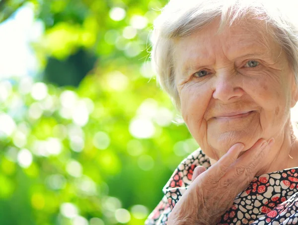 Senior woman smiling and dreaming in garden. — Stock Photo, Image