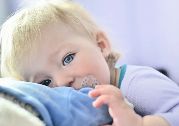 Cute baby with blue eyes hugging a mascot. — Stock Photo, Image