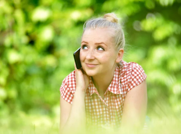 Young attractive woman lying on lawn with phone. — Stock Photo, Image