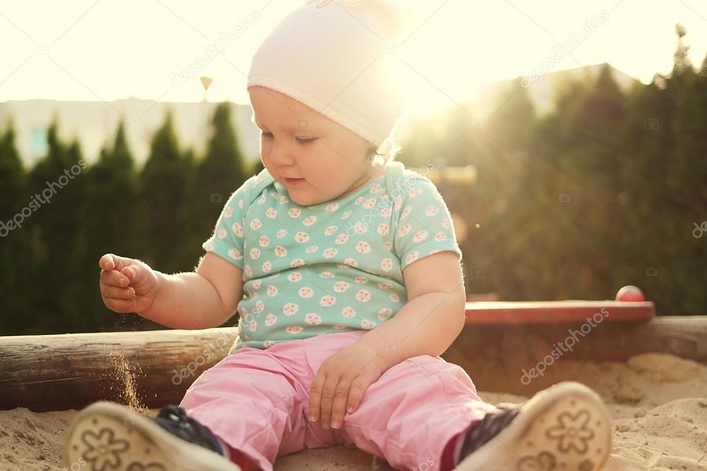 Cute baby on grass in sandbox.