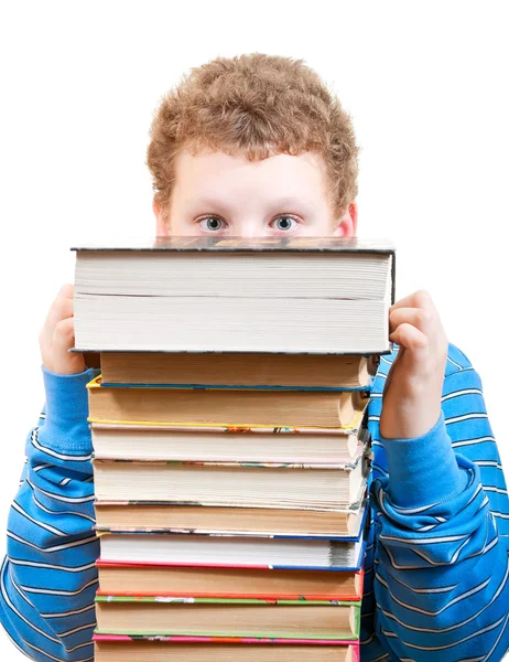 Surprised boy looks out from behind a pile of books — Stock Photo, Image