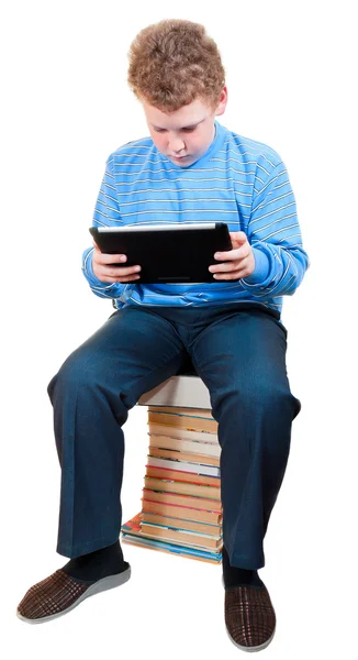 Boy with tablet computer sitting on a pile of books — Stock Photo, Image