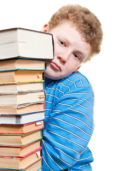 Trieste jongen kijkt uit achter een stapel boeken — Stockfoto