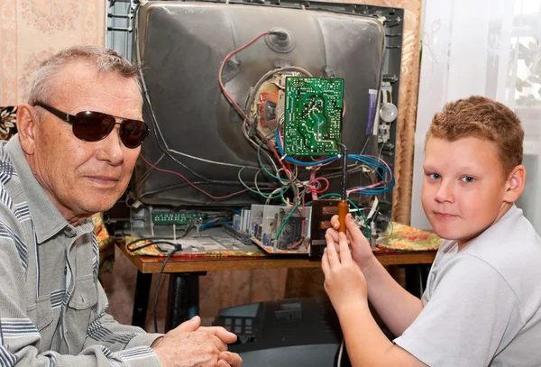 Grandfather and grandson are repairing an old TV — Stock Photo, Image