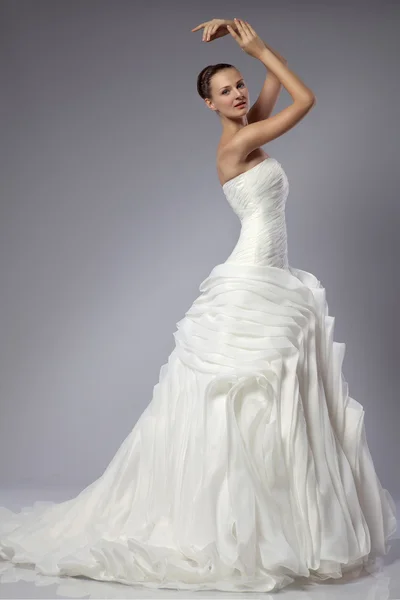 Menina bonita em um vestido de noiva em um fundo cinza — Fotografia de Stock