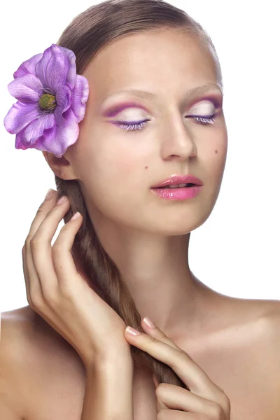 Schöne Mädchen mit einer lila Blume im Haar und Make-up in Fliedertönen — Stockfoto
