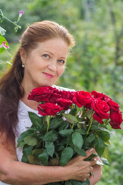 Hermosa mujer en edad de jubilación con un ramo de rosas rojas — Foto de Stock