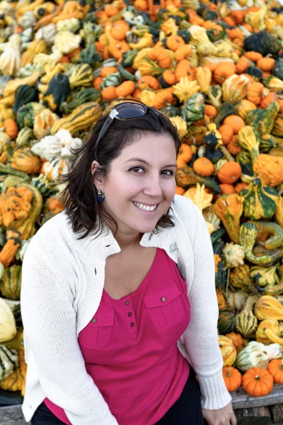 Mujer joven con un montón de calabazas ornamentales — Foto de Stock