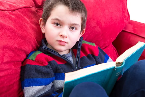 Ребенок читает книгу на диване — стоковое фото