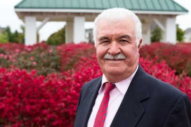 beyaz saç üst düzey iş adamı dışarıda kırmızı yanan çalılar tarafından