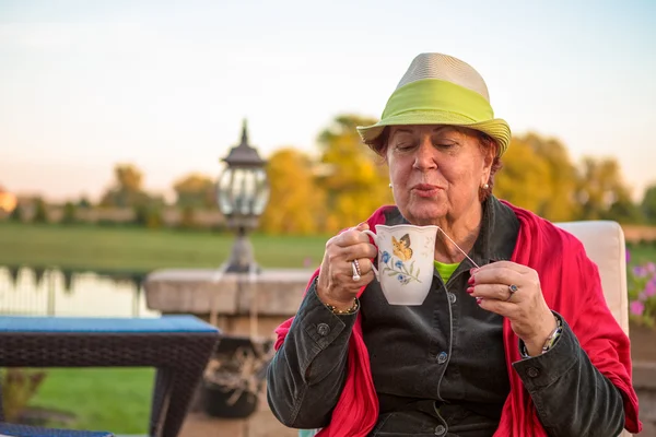 彼女の熱いお茶を吹いて茶時間の年配の女性 — ストック写真