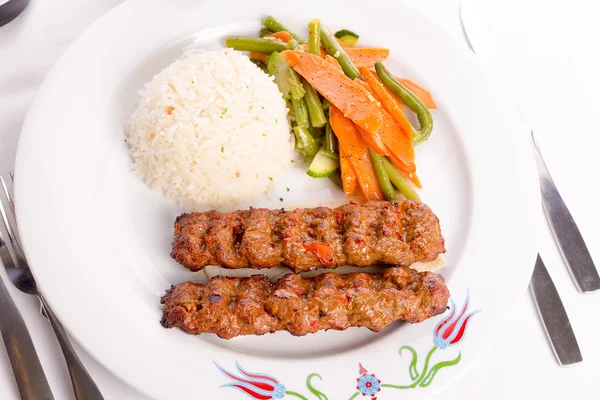 Adana kebab serveras på en lavash bröd garnerad med grönsaker — Stockfoto