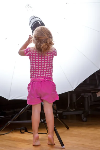 Pequeña niña bonita ajustando el conjunto de equipos de iluminación — Foto de Stock