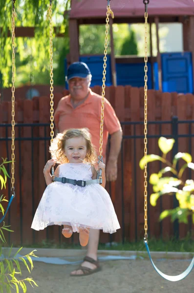 Ragazza bambino sull'altalena spinto da suo nonno — Foto Stock