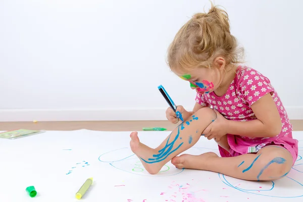 Schattig peuter schilderen haar benen zorgvuldig — Stockfoto