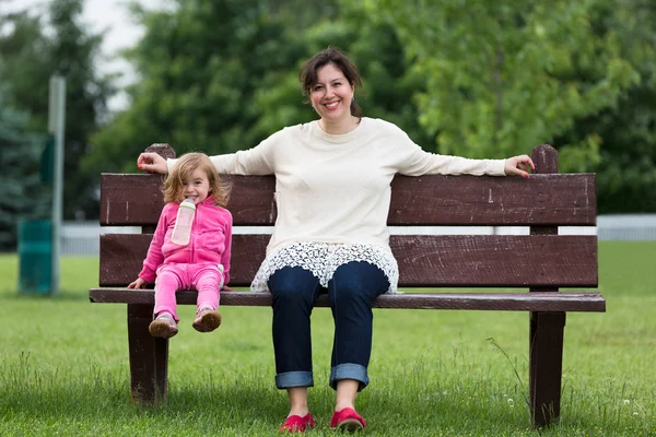 Matka a její dcera zábavě venku na lavičce — Stock fotografie