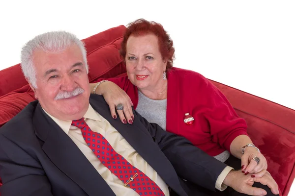 Starszy para siedzi na czerwonej kanapie — Zdjęcie stockowe
