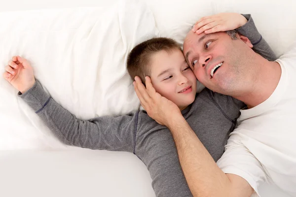 Father and his young son playing in bed Royalty Free Stock Photos