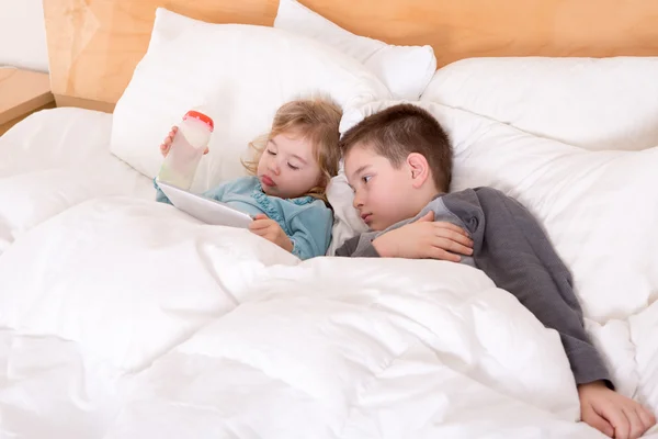 Feliz hermanito y hermana acostados en la cama — Foto de Stock