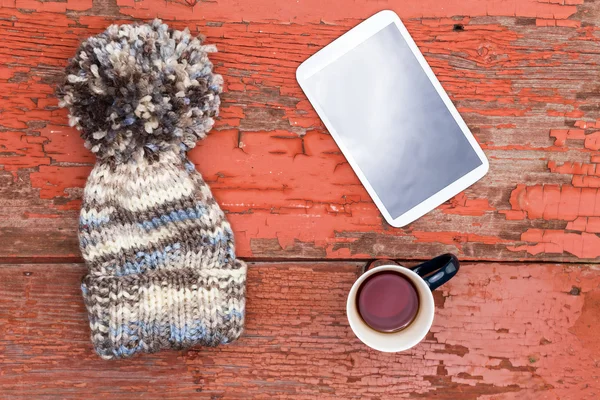 Acogedora gorra de invierno, tableta y té en una mesa grumosa — Foto de Stock