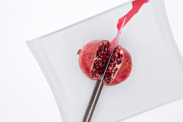 Fresh pomegrate being cut in half with a knife — Stock Photo, Image