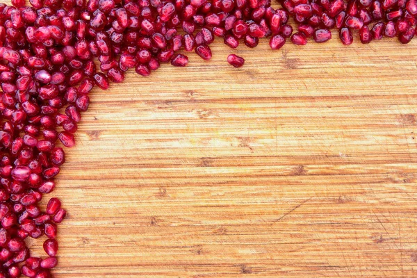Border of pomegranate seed on a wood background — Stock Photo, Image