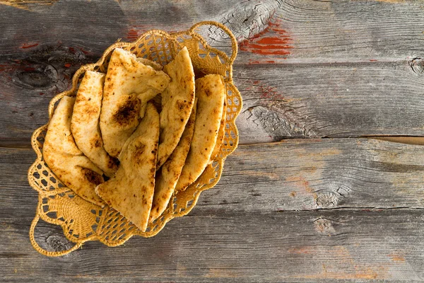 Deliciosas rebanadas de pan plano crujiente naan en una canasta — Foto de Stock