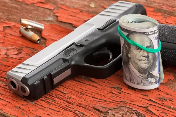 Pistola con un rollo de billetes de 100 dólares — Foto de Stock