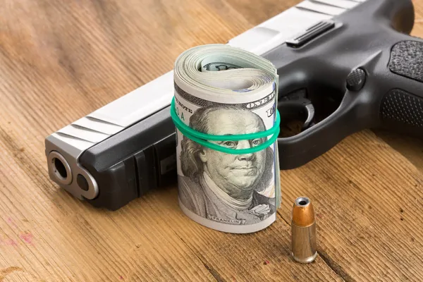Handfeuerwaffe mit einer Rolle Dollarscheine und einer Kugel — Stockfoto