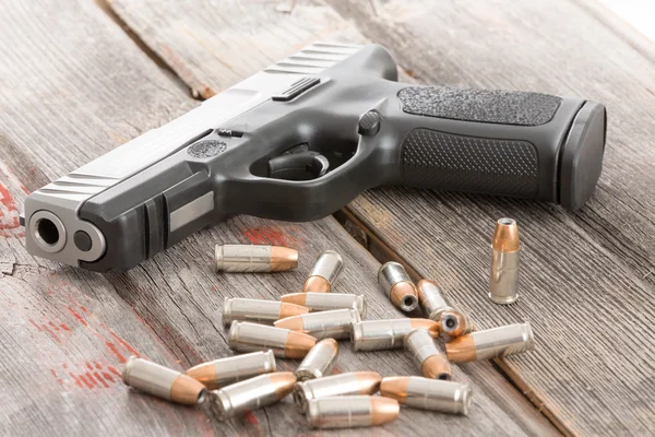 Handgun en opsommingstekens liggend op een houten tafel — Stockfoto