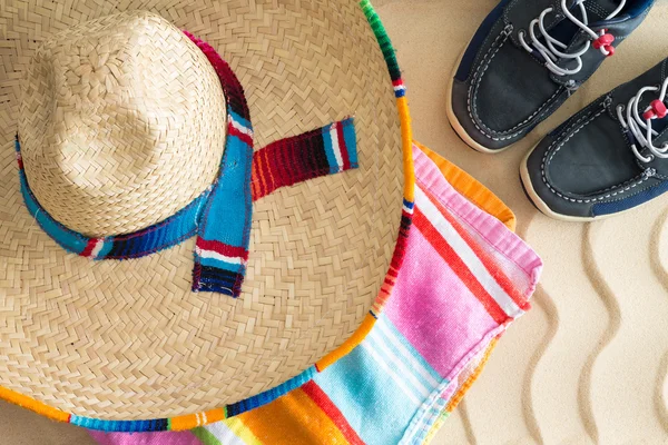 Sombrero, beach towel and sneakers on sand — Stock Photo, Image