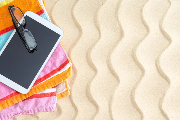 Tablett och glasögon på en färgglad stranden handduk — Stockfoto