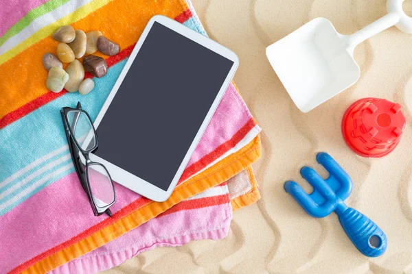 Komputer typu Tablet na ręcznik plażowy, szklanki i zabawki — Zdjęcie stockowe