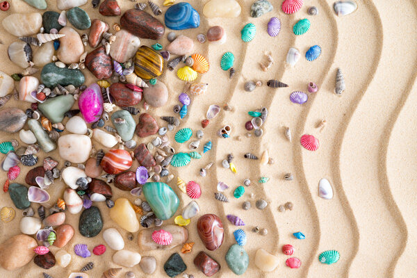 Pebbles, gemstones and shells on beach sand