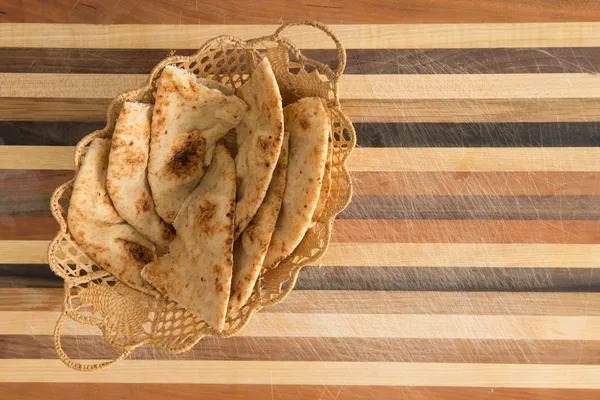 Cudownie pieczone naan flatbread plastry w kosz na deski do krojenia — Zdjęcie stockowe