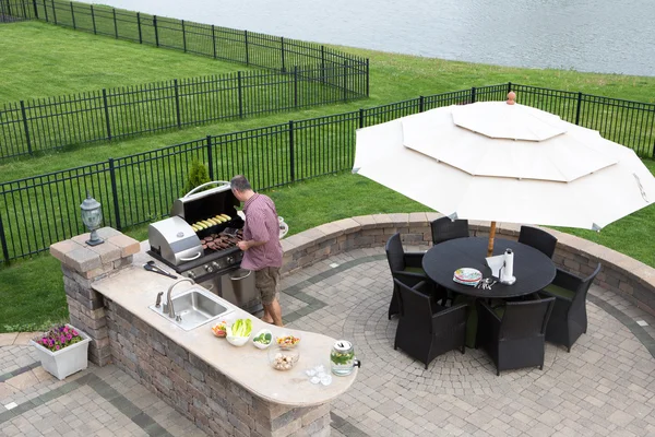 Homme cuisinant de la viande sur un barbecue à gaz — Photo