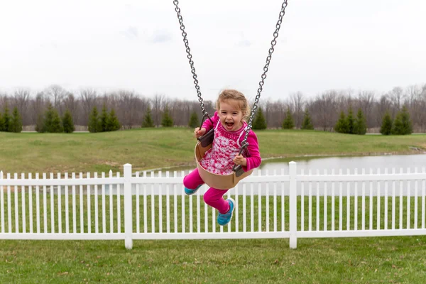 Beautiful excited little girl on a swing — Stock Photo, Image