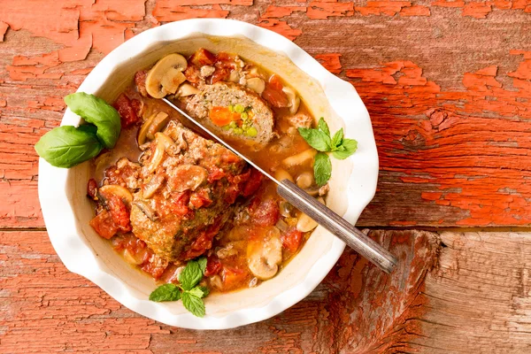 Pan de carne en rodajas en una cazuela sobre una mesa rústica — Foto de Stock