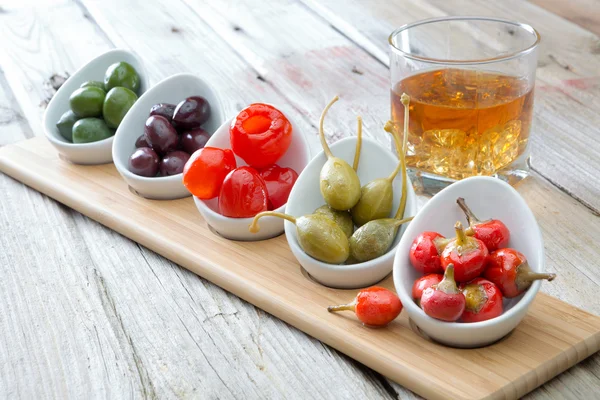 Selection of olives and peppers with whiskey — Stock Photo, Image