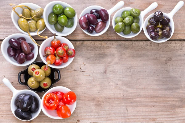 Border of olives and peppers on a wooden counter — Stock Photo, Image