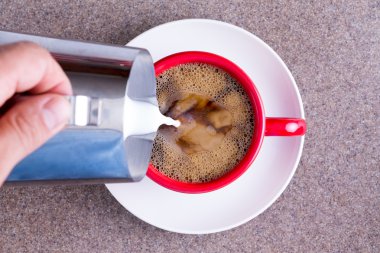 Man pouring milk into black coffee clipart