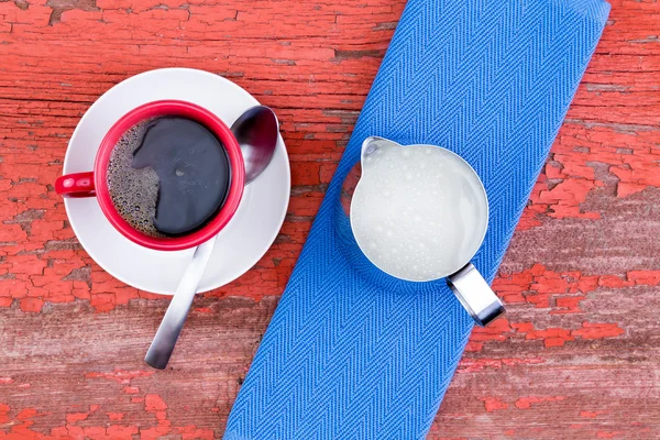 Cup of black coffee on a rustic red picnic table — Stock Photo, Image