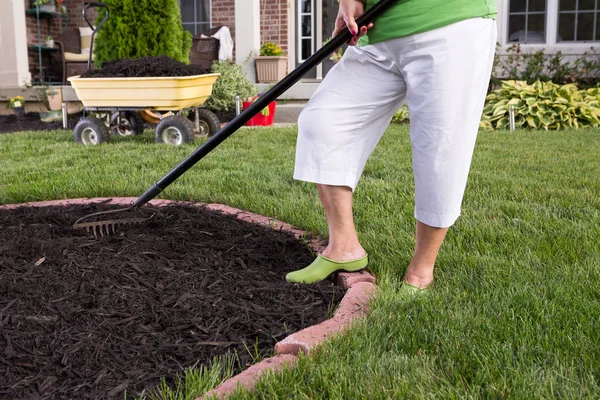 Senior mulher mulching um canteiro de flores — Fotografia de Stock